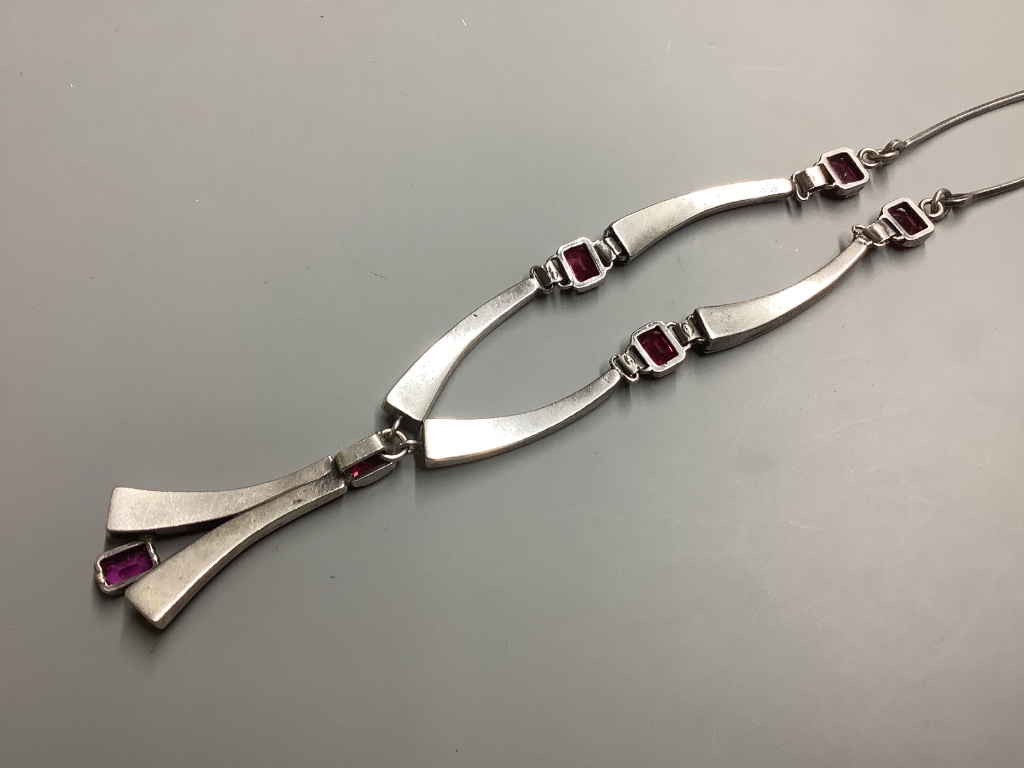A modern stylish white metal and synthetic ruby set drop pendant necklace, 55 cm.